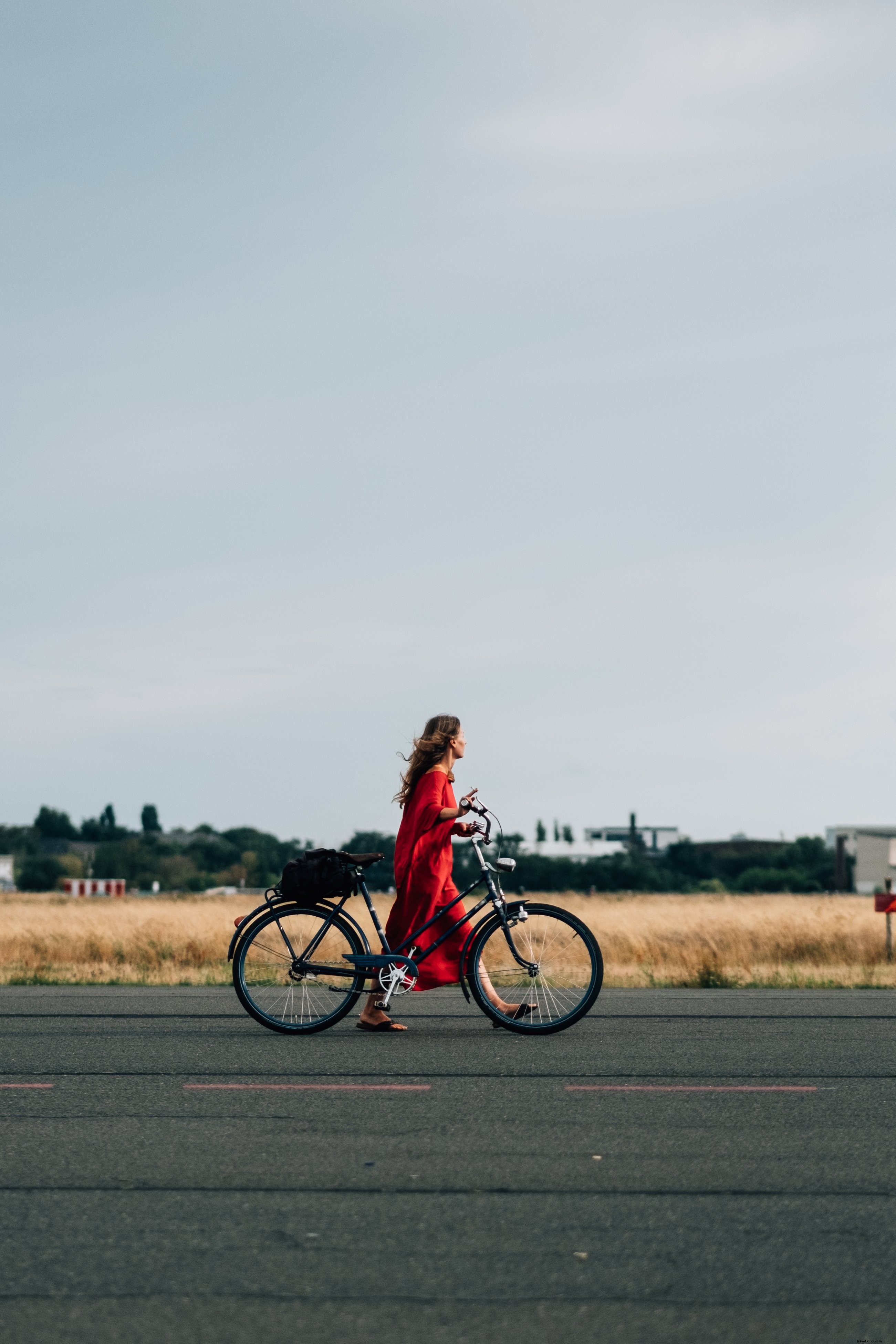赤いドレス姿の人物が自転車で道を走る写真