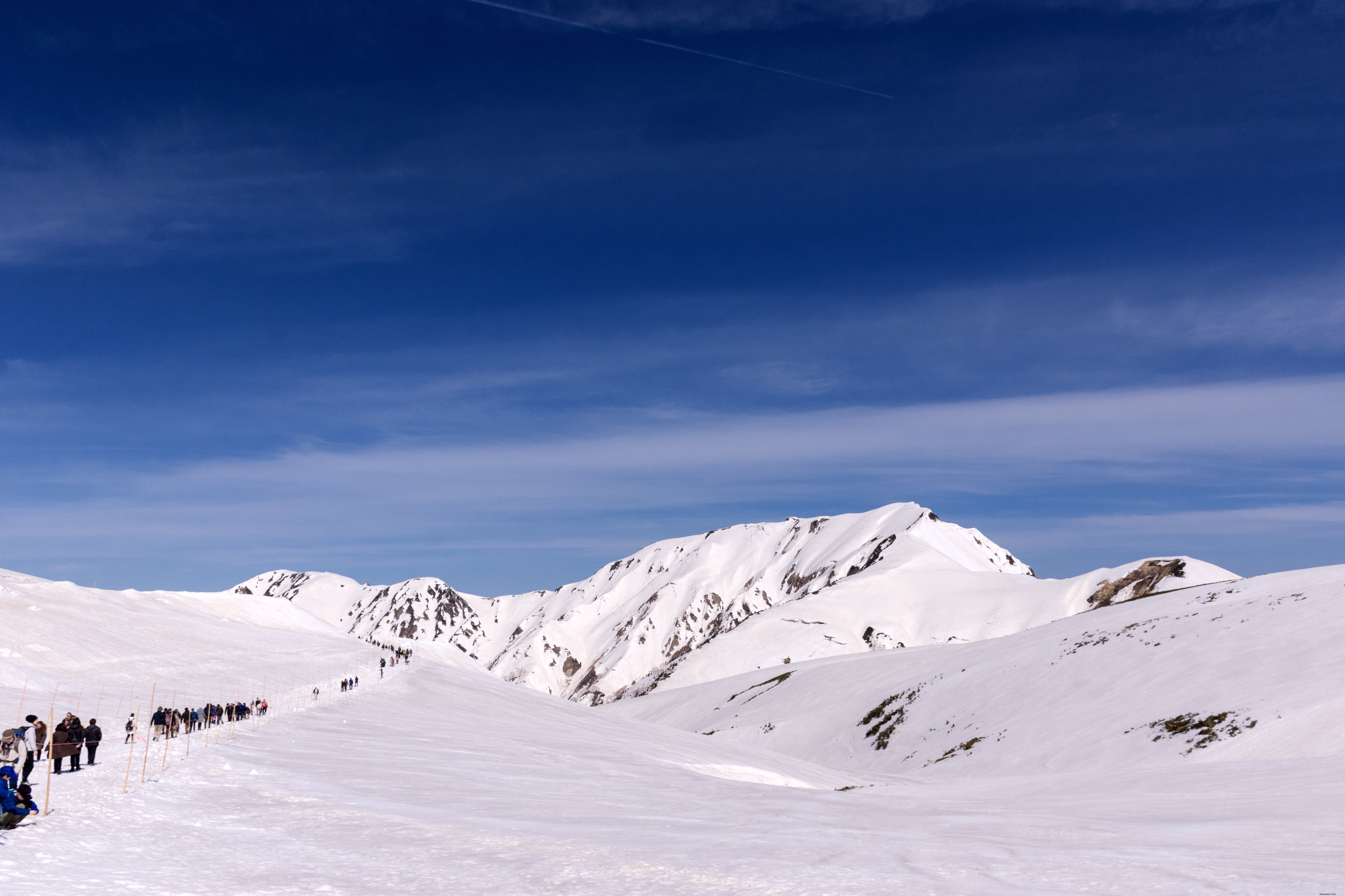 雪に覆われた山々を横断するハイカーの列