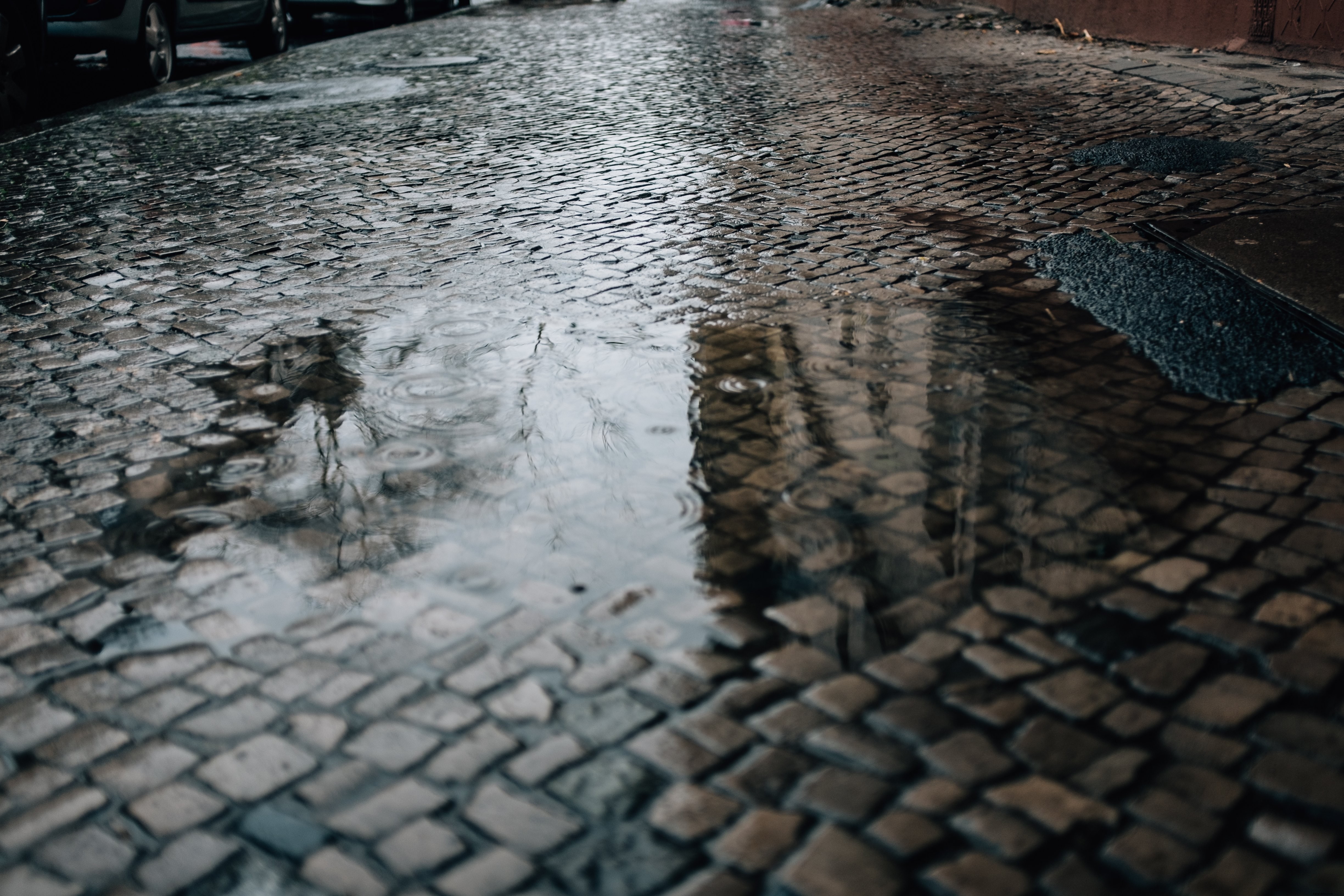 石畳の路上にできた水たまりの写真