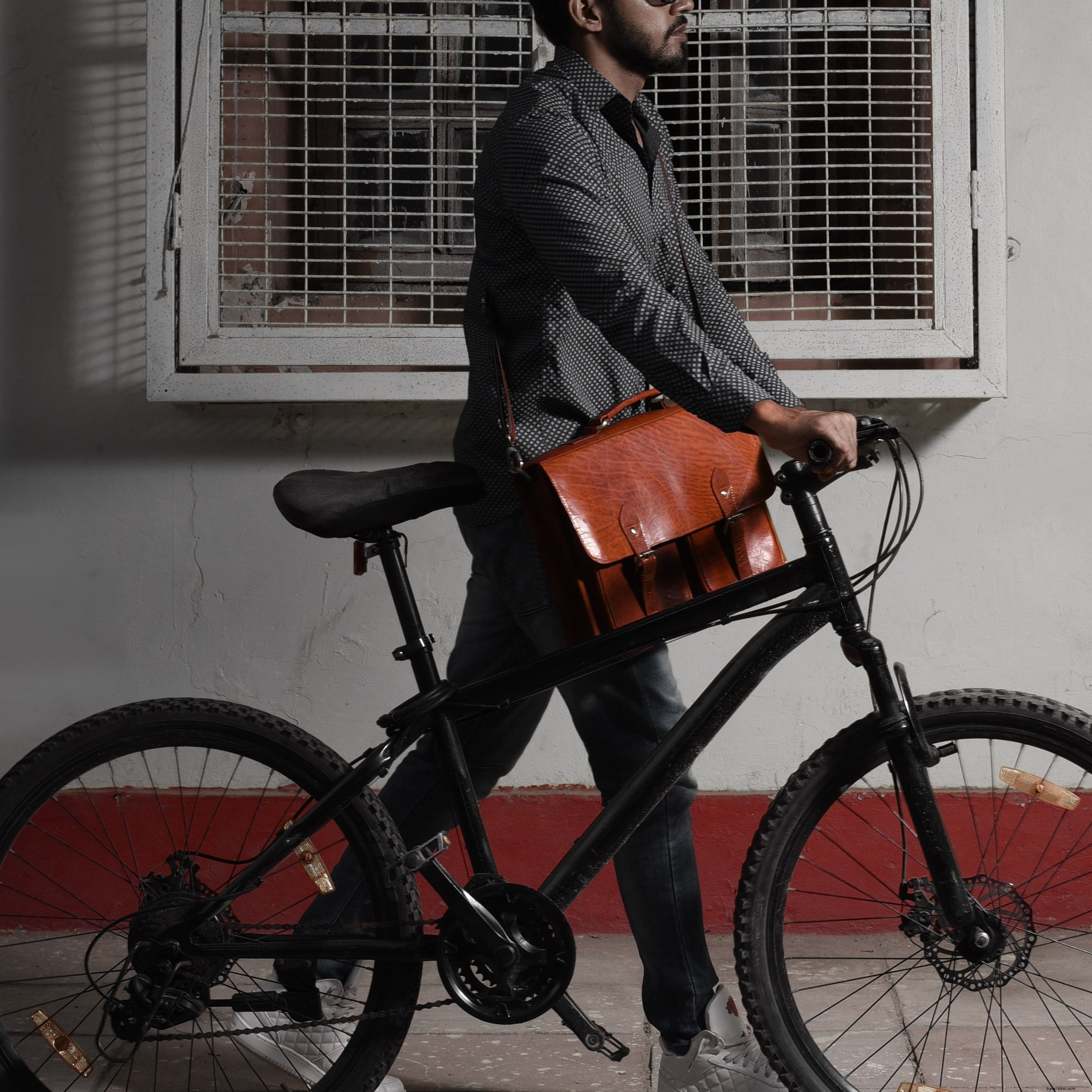 革製メッセンジャーバッグを背負って自転車に乗る人