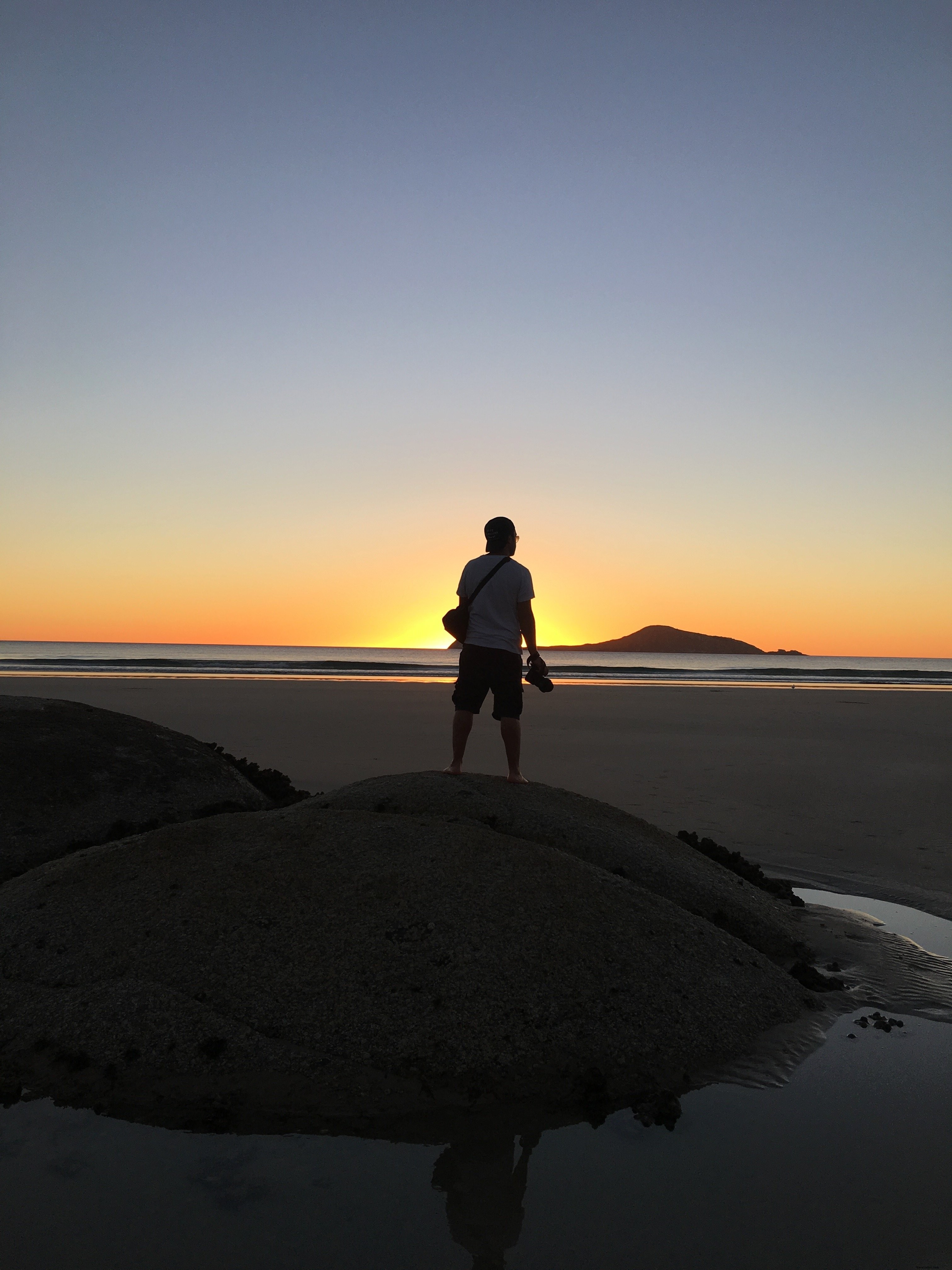 砂丘の男性がビーチで夕日を眺める写真