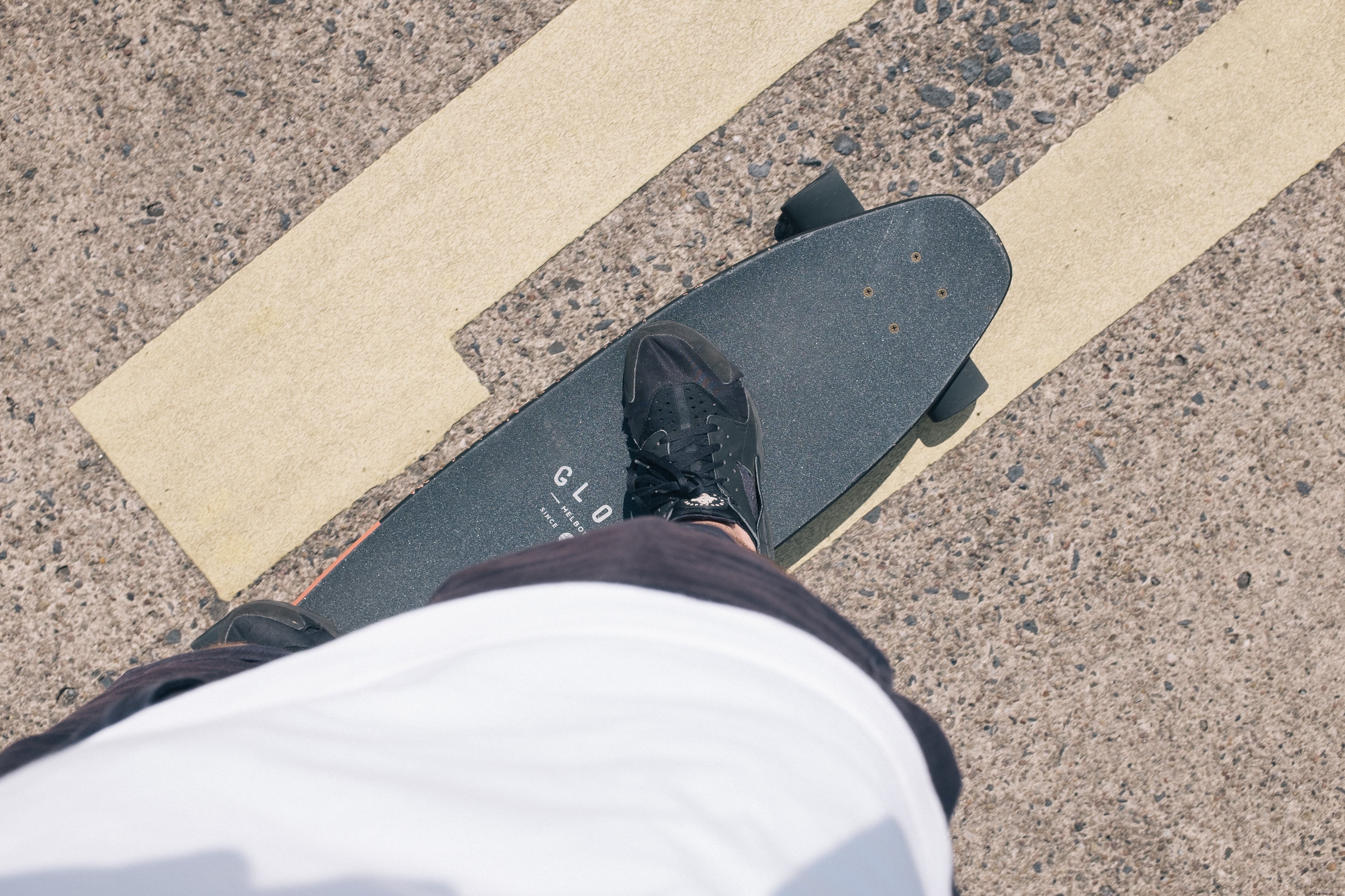 舗装道路で黒いスケートボードに乗る人の写真