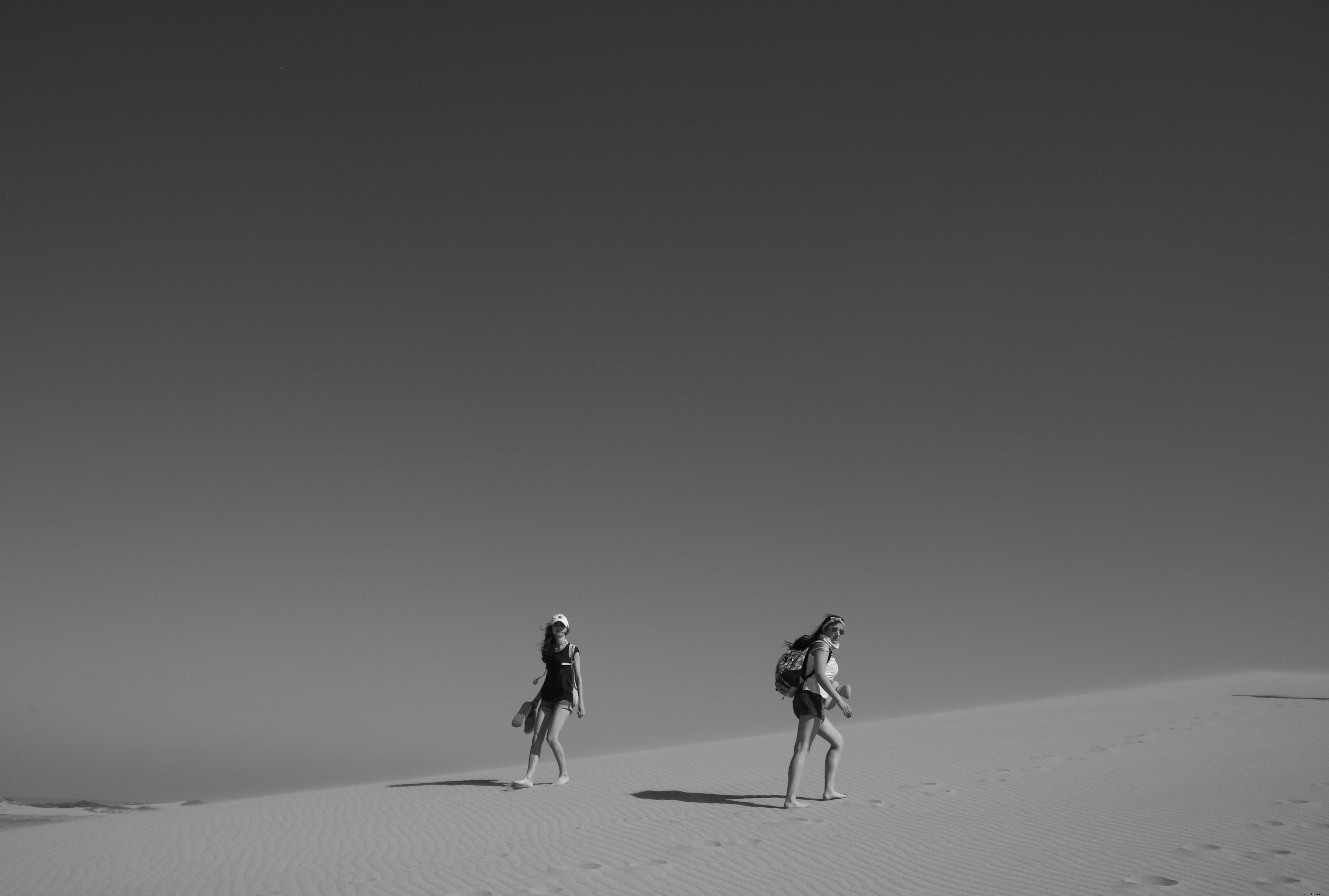 砂漠を歩く人々のモノクロ写真