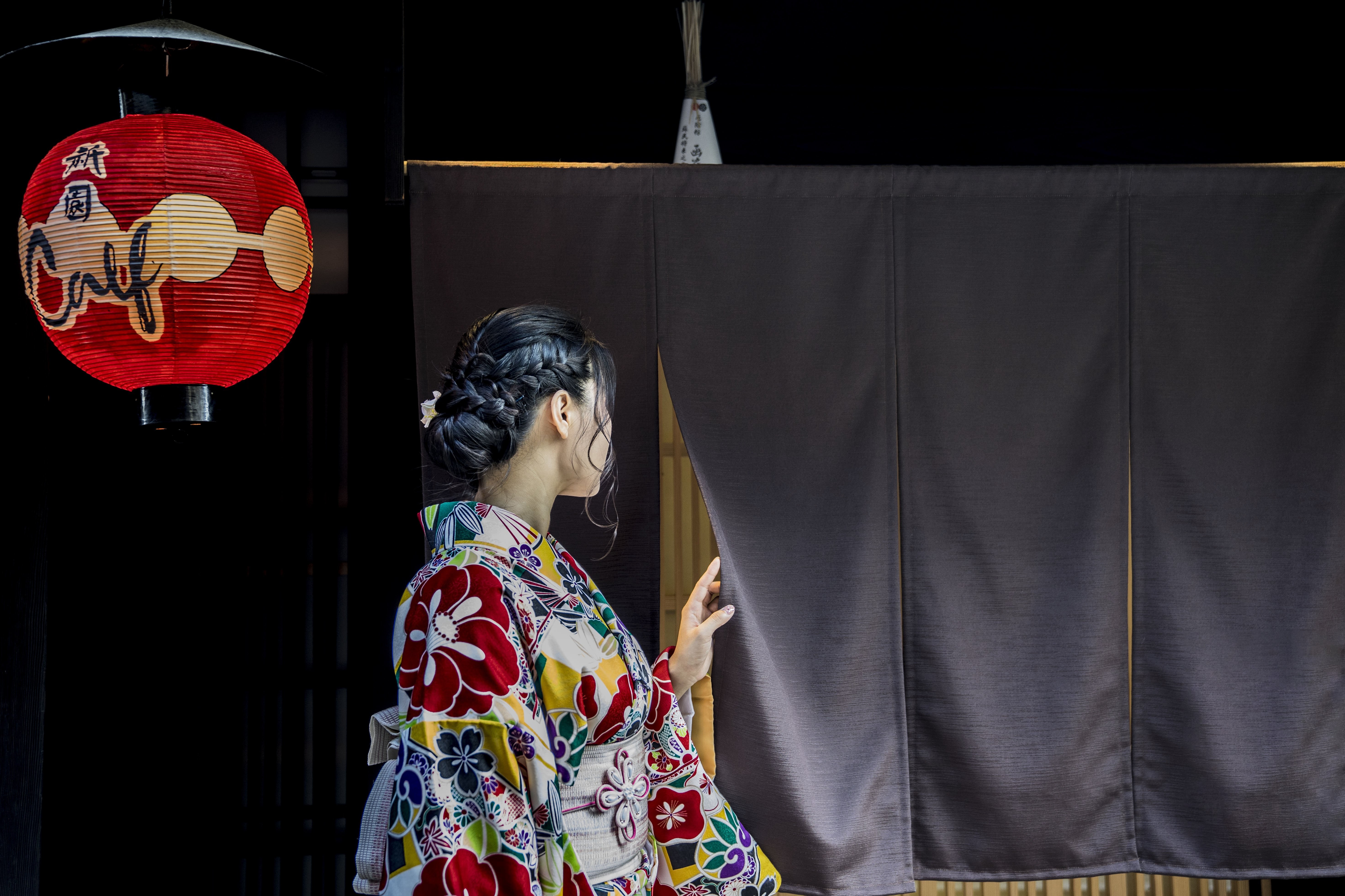 黒いカーテンの後ろで着物姿の人物写真