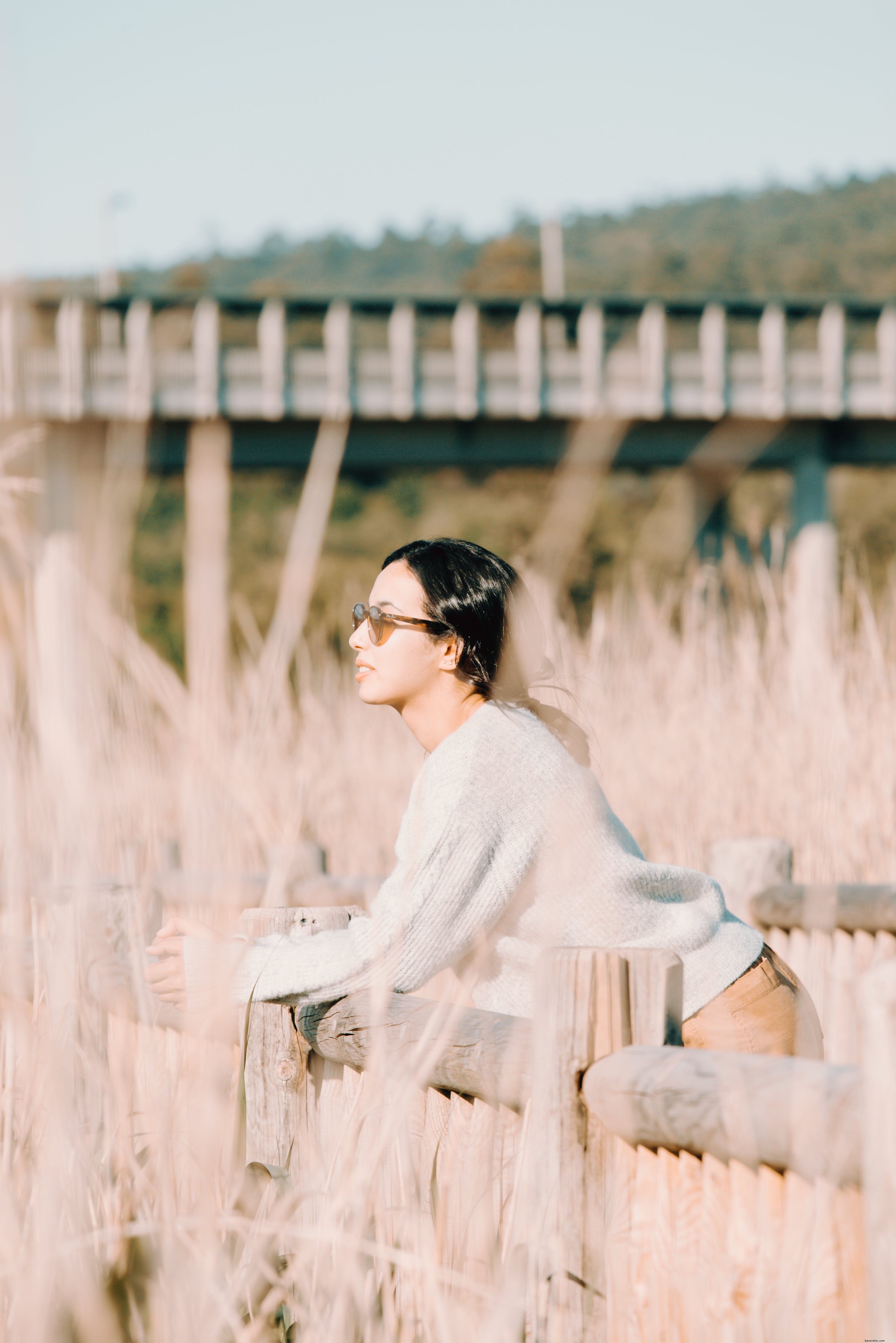 屋外の木製フェンスでくつろぐ女性の写真