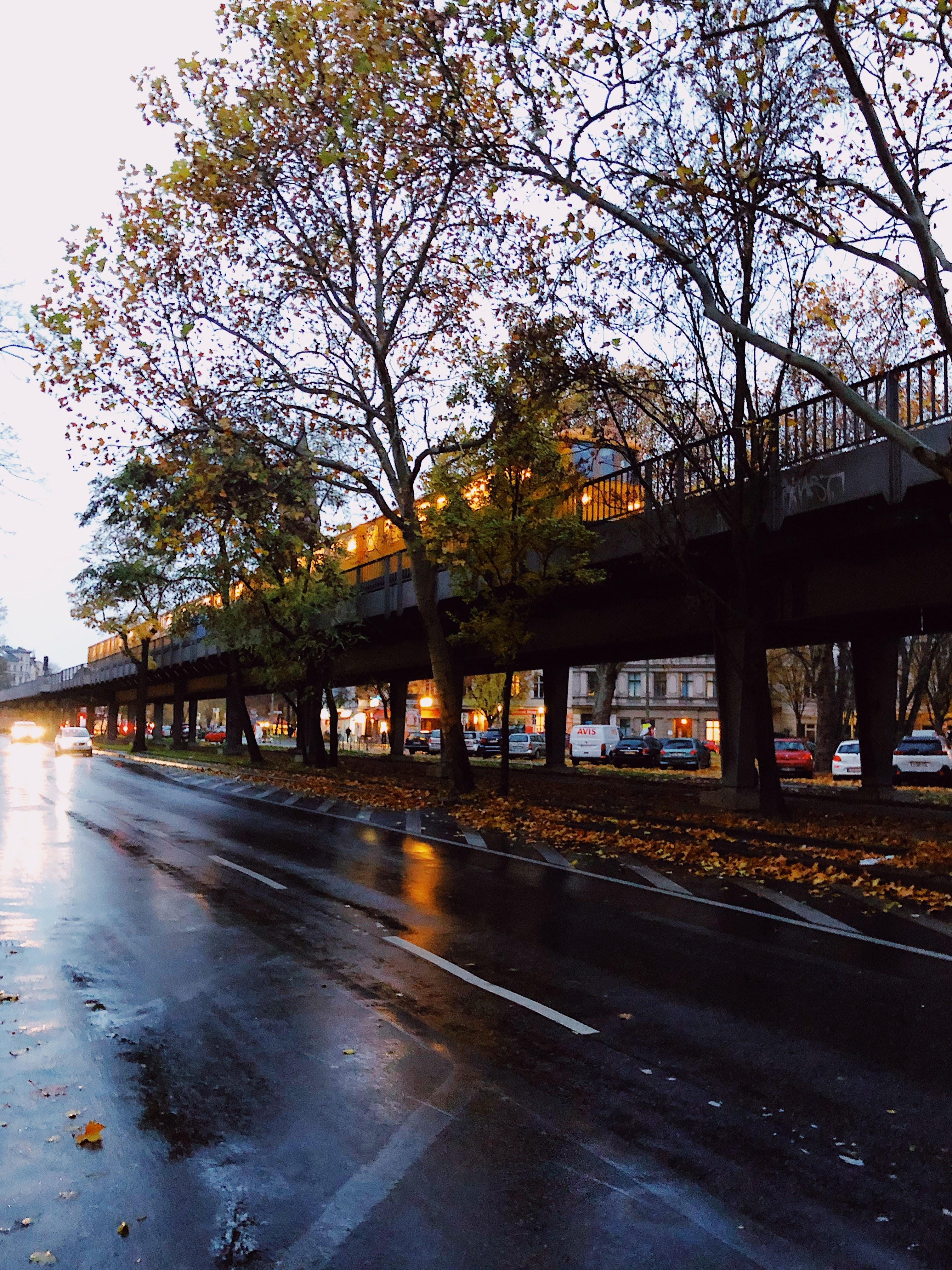 雨の道路に映るトラックと黄色い電車の写真